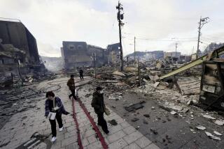 People walk past collapsed buildings following an earthquake in Wajima, Ishikawa prefecture, Japan Tuesday, Jan. 2, 2024. A series of powerful earthquakes in western Japan damaged homes, cars and boats, with officials warning people on Tuesday to stay away from their homes in some areas because of a continuing risk of major quakes and tsunamis. (Kyodo News via AP)