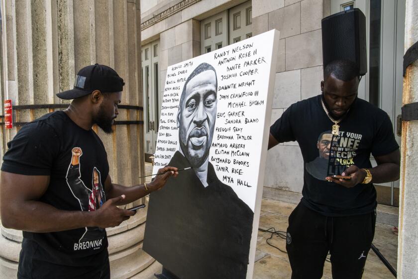 Artist Dennis Owes, 31, from Ghana gives the last touch to his portrait of George Floyd during a rally on Sunday, May 23, 2021, in Brooklyn borough of New York. George Floyd, whose May 25, 2020 death in Minneapolis was captured on video, plead for air as he was pinned under the knee of former officer Derek Chauvin, who was convicted of murder and manslaughter in April 2021. (AP Photo/Eduardo Munoz Alvarez)