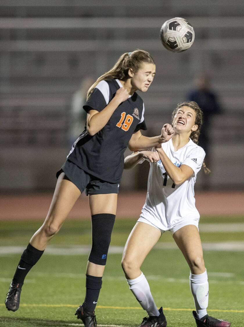 Huntington Beach's Liz Johnson and Corona del Mar's Isabella Thomas go up for a header during a Surf League game on Tuesday.