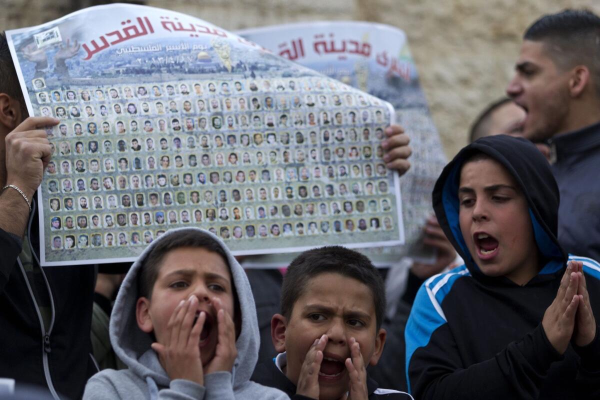 Palestinian children shout slogans before a large poster showing the names of over 100 Palestinians from Jerusalem who are currently held in Israeli prisons during a protest Wednesday at the Damascus Gate in Jerusalem. A critically ill Palestinian prisoner was released Thursday for what Israel said were humanitarian reasons.