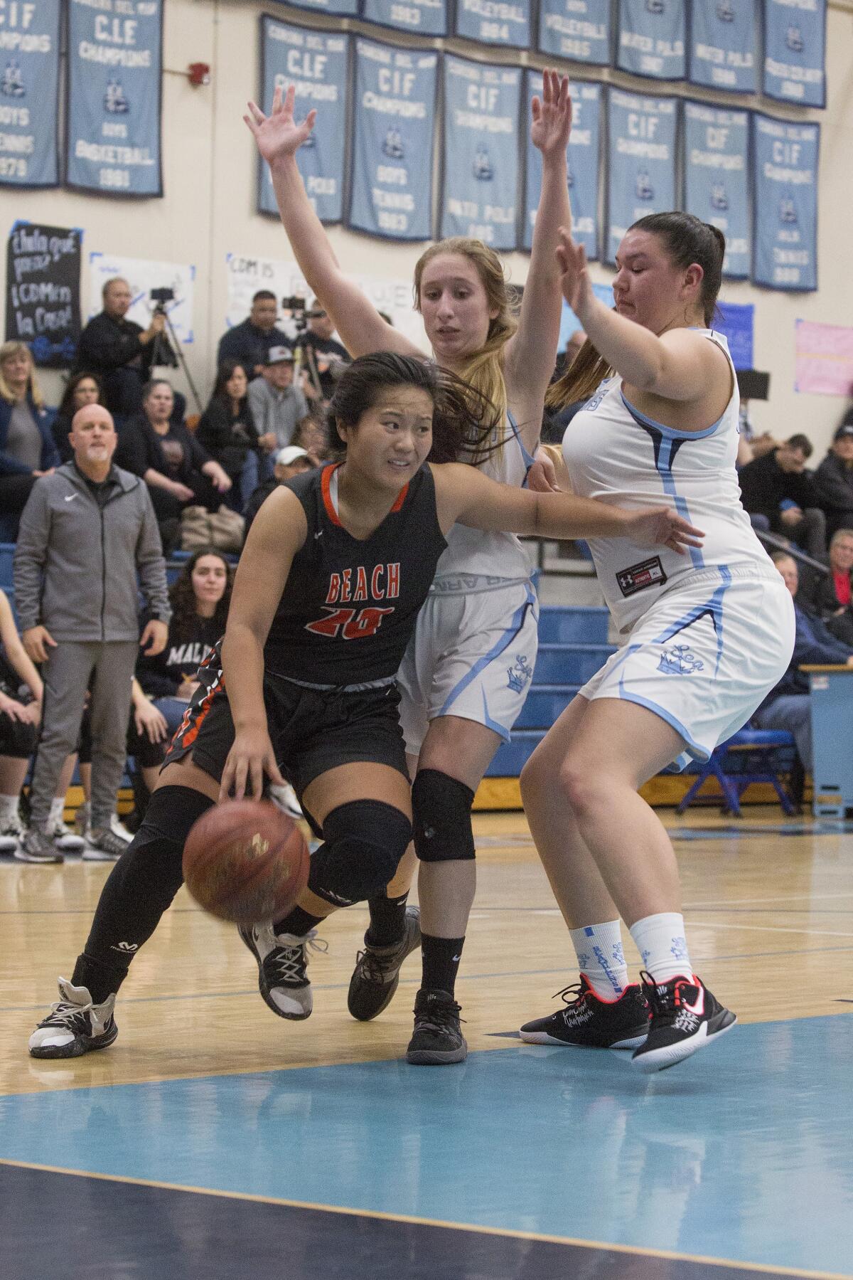 Huntington Beach’s Marisa Tanga (20) drives baseline against Corona del Mar’s Tori Gyselaar and Makena Tomlinson during a Surf League game on Thursday.