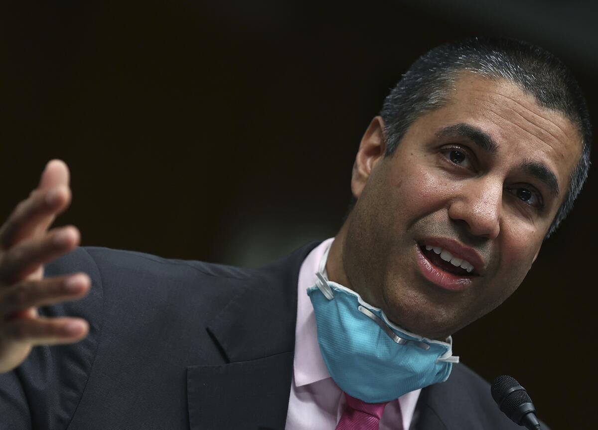 Ajit Pai gestures and speaks into a microphone as he testifies before a Senate panel in June.