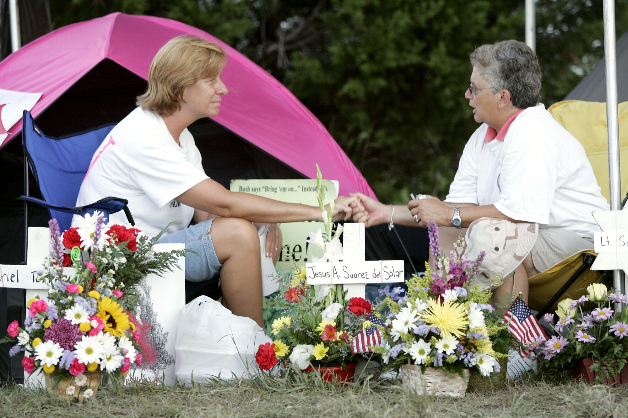 Cindy Sheehan holds hands with Sue Niederer at a makeshift camp near the ranch of President Bush