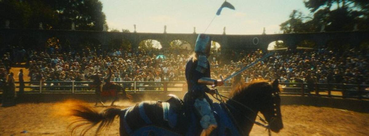 A person on horseback in an arena with a crowd of spectators 