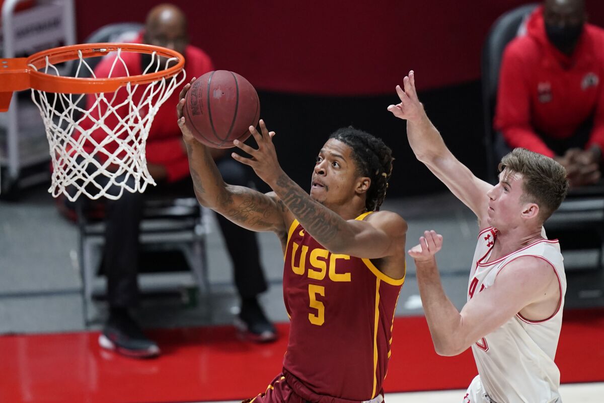 USC guard Isaiah White, left, drives to the basket ahead of Utah center Branden Carlson.