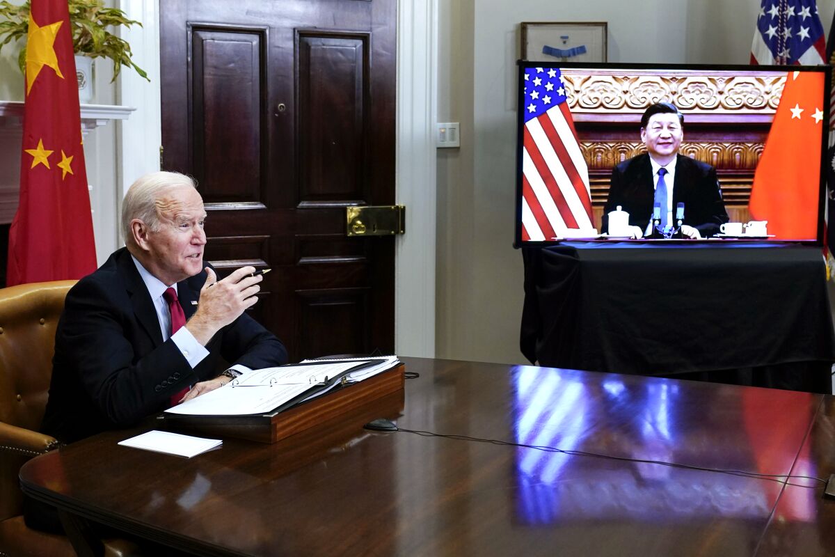 President Biden at a table; Xi Jinping on a video monitor beside Biden