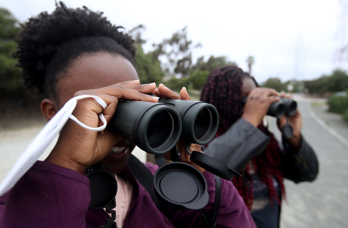 Two women look through binoculars.