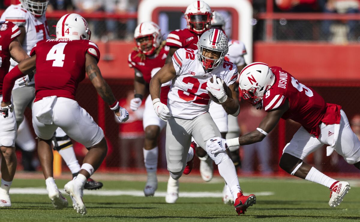 Ohio State's TreVeyon Henderson (32) rushes against Nebraska's Myles Farmer (4) and Marquel Dismuke (9) during the second half of an NCAA college football game Saturday, Nov. 6, 2021, at Memorial Stadium in Lincoln, Neb. Ohio State defeated Nebraska 26-17. (AP Photo/Rebecca S. Gratz)
