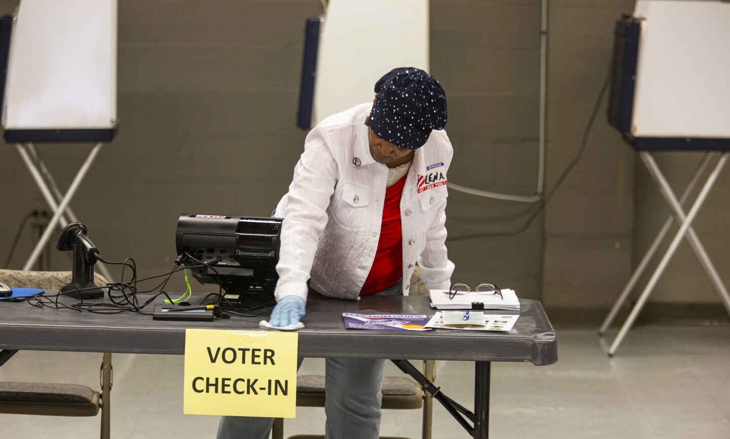 Leon County, Florida poll worker Lena Simmonds wipes up a voter check-in counter while waiting on voters to arrive on March 17, 2020 in Tallahassee, Florida.