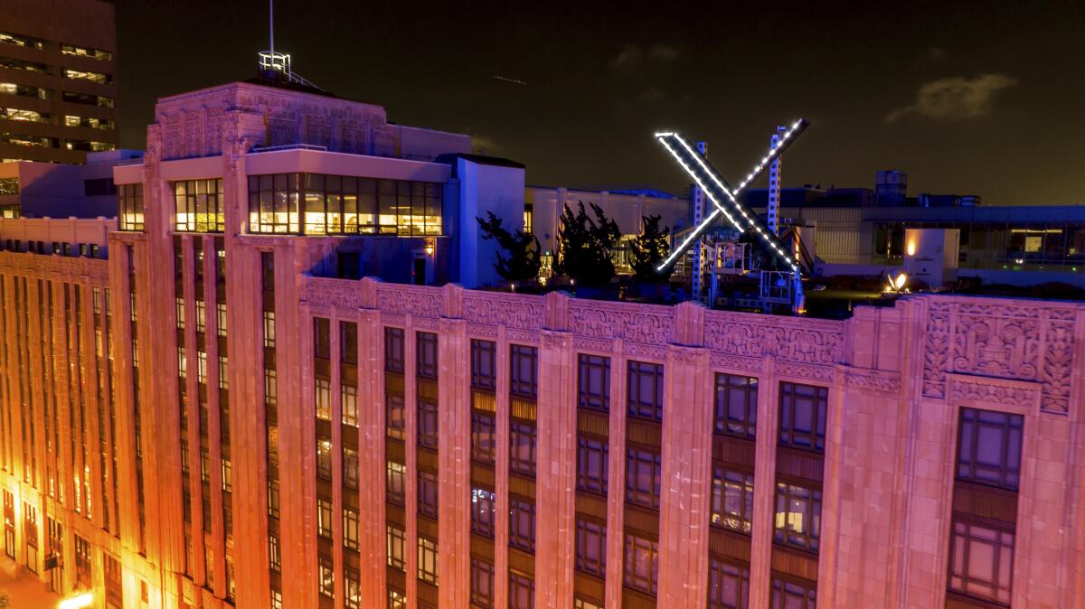 Workers install lighting on an "X" sign atop the company headquarters.