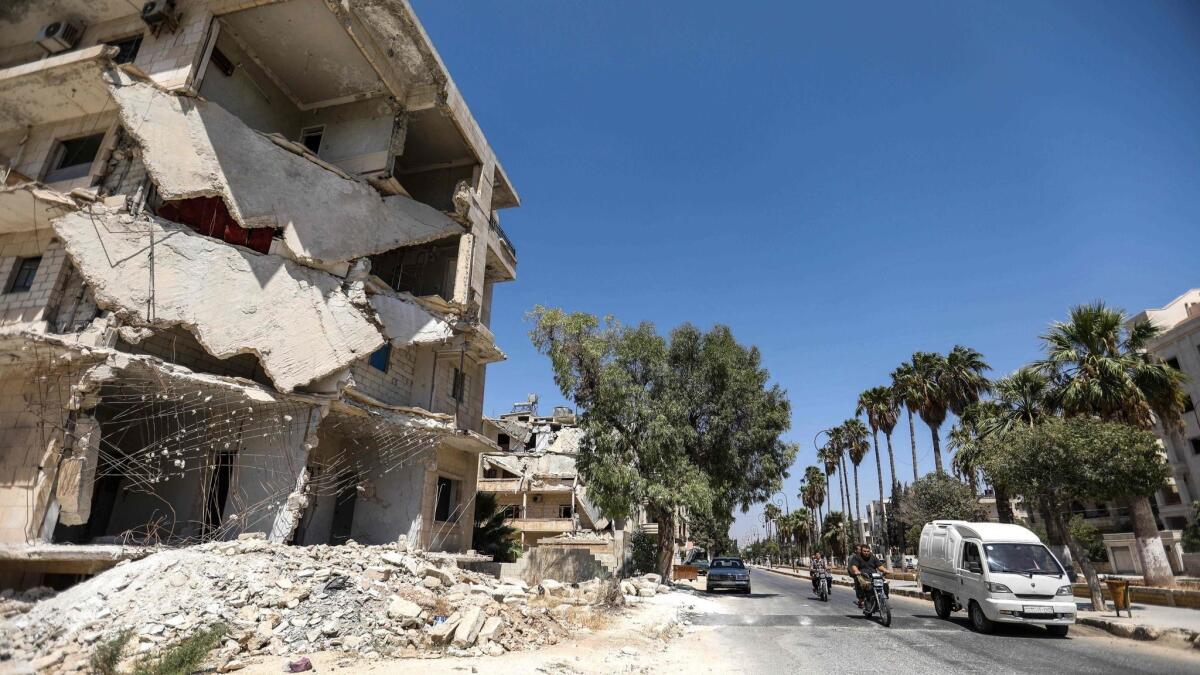 Motorists pass a damaged building in the rebel-held northern Syrian city of Idlib.