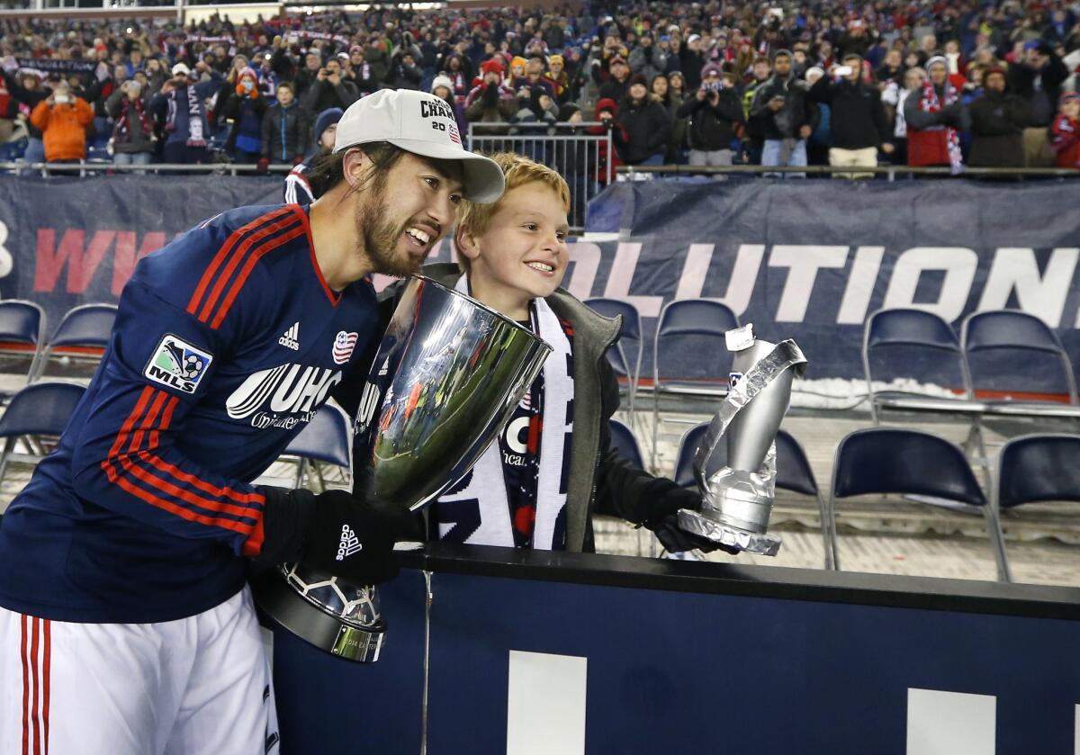 New England midfielder Lee Nguyen holds the Eastern Conference Champion's Cup as he poses with a fan following the Revolution's 2-2 draw with the New York Red Bulls. New England advanced to the MLS Cup on aggregate goals, 4-3.