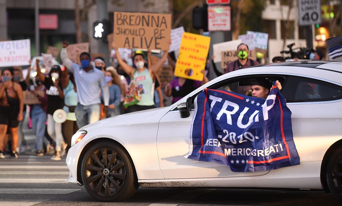 A driver displays a Trump flag at people marching in support of Breonna Taylor in Sherman Oaks in 2020. 