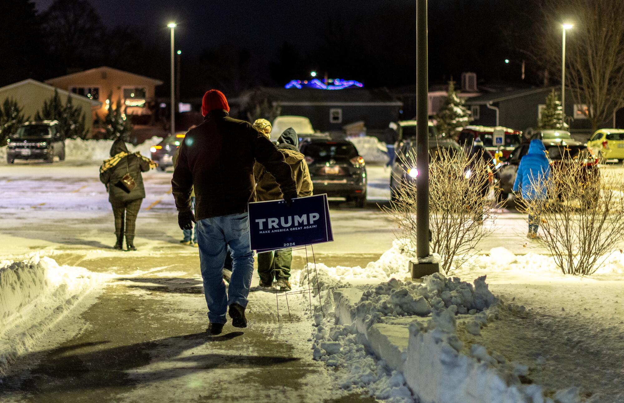 A caucus goer leaves with a Trump sign after Trump won the Iowa Caucuses.