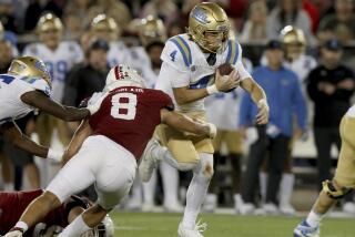 UCLA quarterback Ethan Garbers holds onto the ball and runs as he is hit by Stanford linebacker Tristan Sinclair