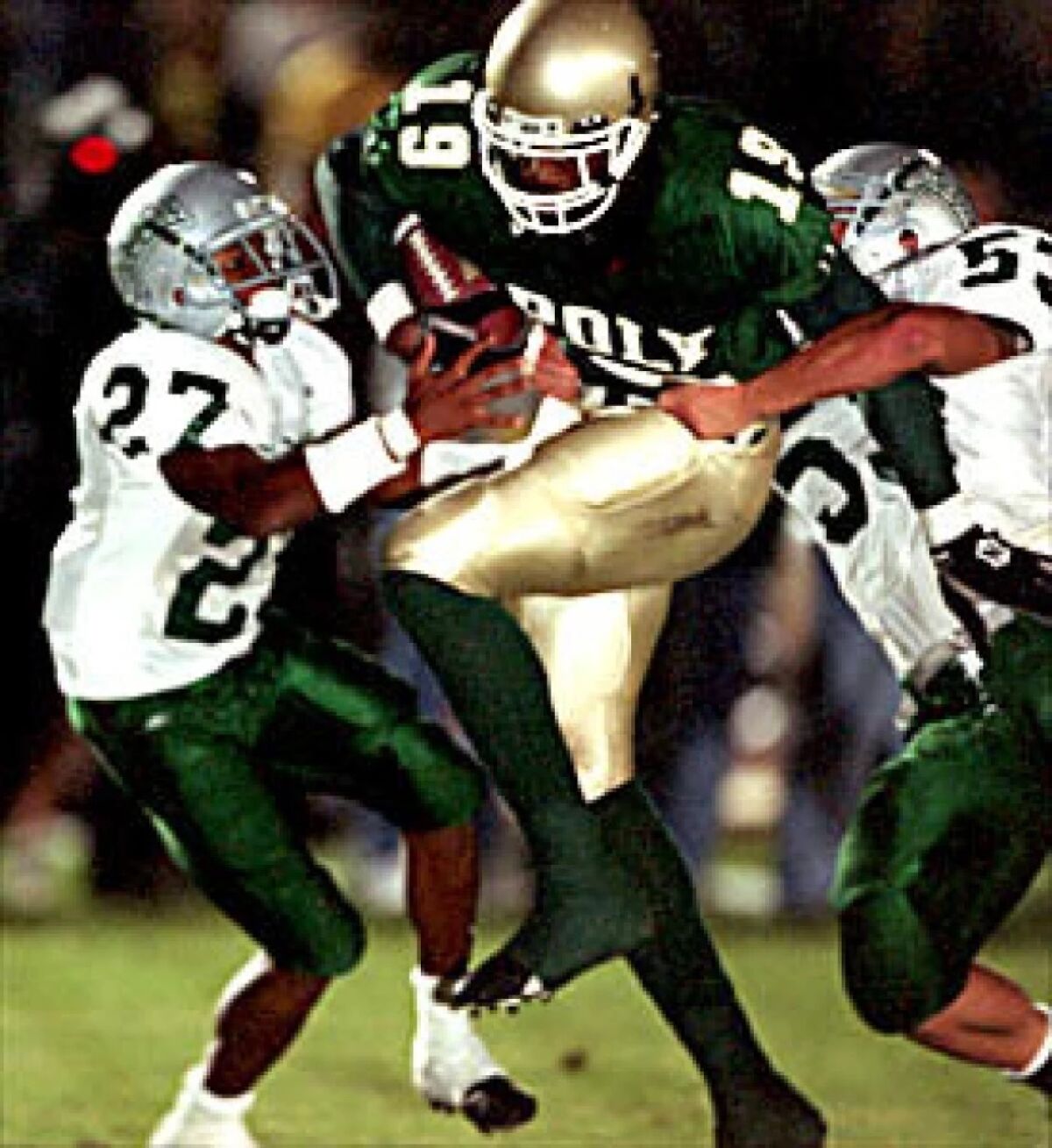 Long Beach Poly tight end Marcedes Lewis tries to get past De La Salle defenders after a reception during a game in 2001.