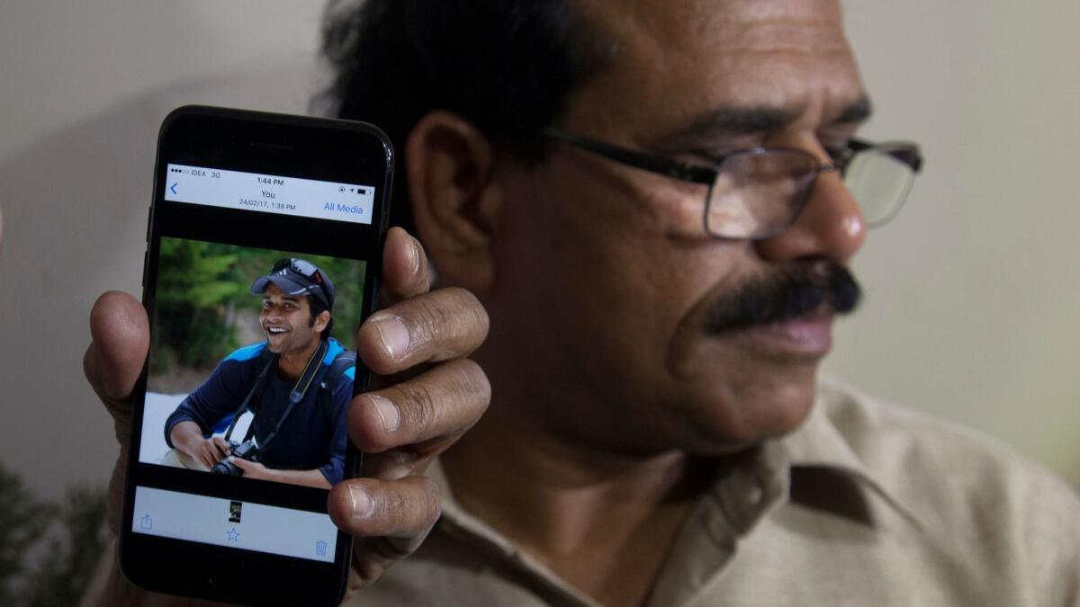 A man in Hyderabad, India, shows a picture of Alok Madasani, the engineer who was injured in the shooting Wednesday night in Kansas.