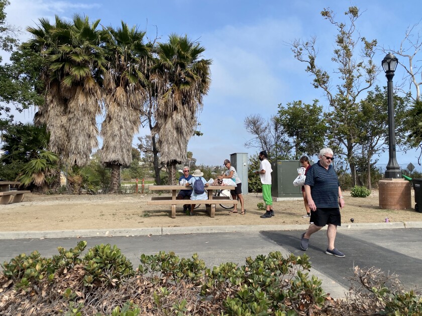 Volunteer Jan Greenberg walks back to the food set up after assisting men at the table at Doheny State Beach on June 16.