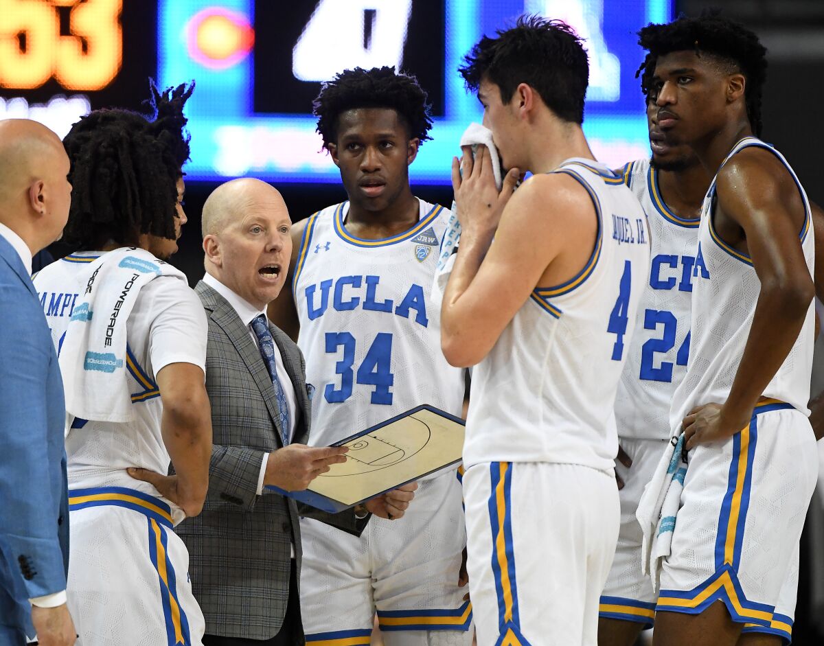 UCLA players Tyger Campbell (10), David Singleton (34), Jaime Jaquez Jr. (4), Jalen Hill (24) and Chris Smith (5) listen as head coach Mick Cronin talks during a timeout in the second half against Arizona at Pauley Pavilion on Saturday.