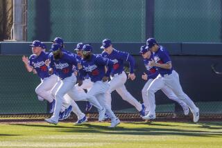 Dodgers players, including Shohei Ohtani, rear, run sprints in the outfield during the first day of spring training.