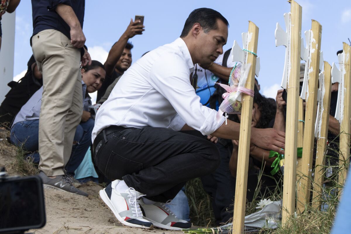Julián Castro places flowers on markers for those who died trying to cross the Rio Grande.