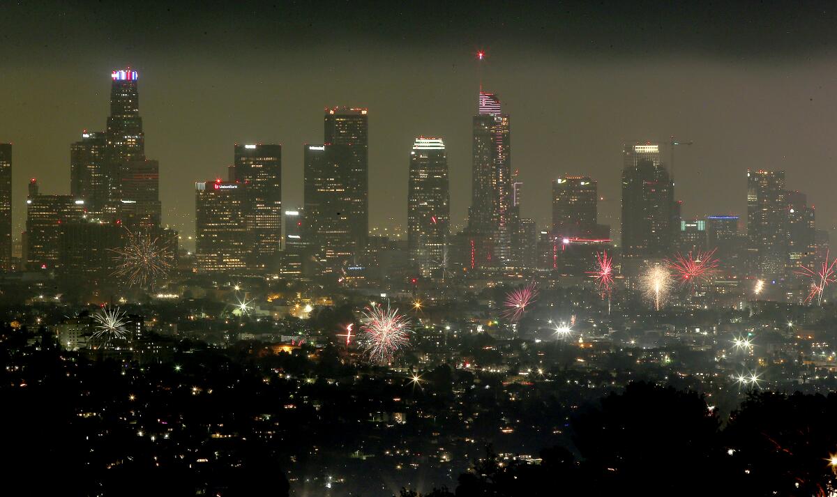 Illegal fireworks explode with the downtown Los Angeles skyline as a backdrop on the Fourth of July in 2022.