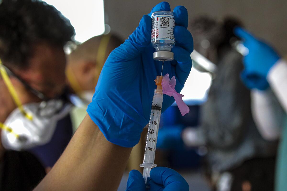 a syringe is filled from an upside down glass vial