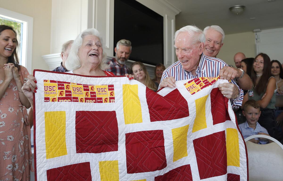 Barbara Winkler of SoCal Quilts of Valor, left, surprises Joseph King with a quilt during his 100th birthday party.