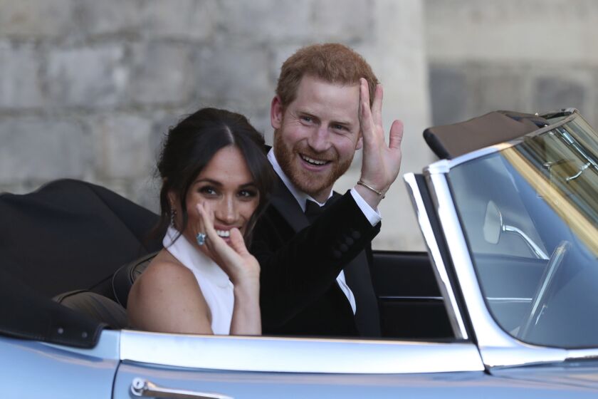 FILE - In this Saturday, May 19, 2018 file photo the newly married Duke and Duchess of Sussex, Meghan Markle and Prince Harry, leave Windsor Castle in a convertible car after their wedding in Windsor, England, to attend an evening reception at Frogmore House, hosted by the Prince of Wales. Prince Harry and his wife Meghan are ending their lives as senior members of Britain’s royal family and starting an uncertain new chapter as international celebrities and charity patrons. In January the couple shocked Britain by announcing that they would step down from official duties, give up public funding, seek financial independence and swap the U.K. for North America. The split becomes official on March 31. (Steve Parsons/pool photo via AP, File)