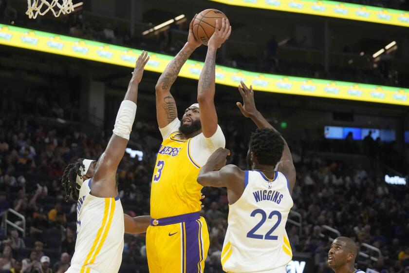 Los Angeles Lakers forward Anthony Davis (3) shoots against Golden State Warriors forwards Kevon Looney, left, and Andrew Wiggins (22) during the first half of an NBA preseason basketball game in San Francisco, Saturday, Oct. 7, 2023. (AP Photo/Jeff Chiu)