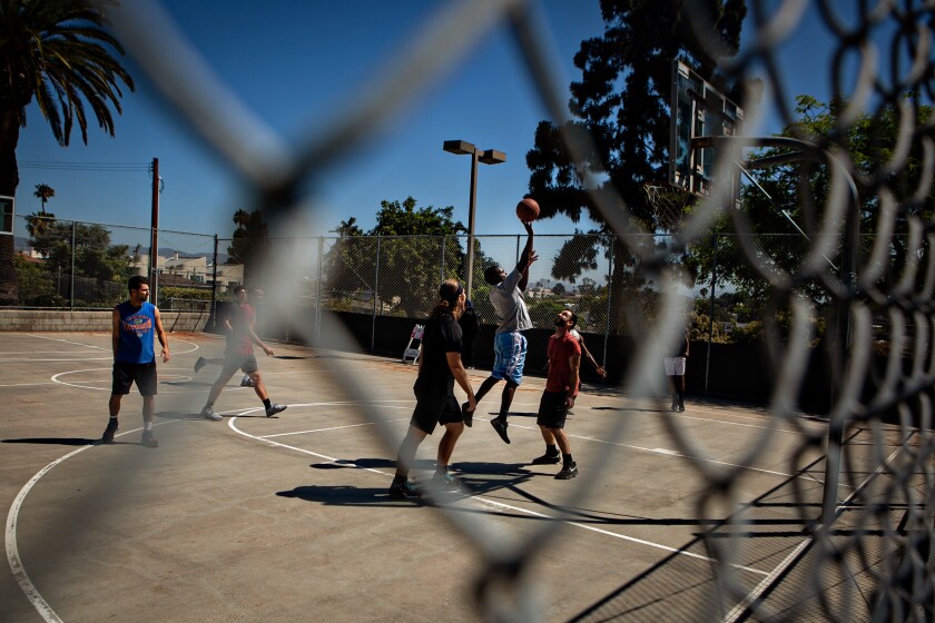 A pickup basketball game seen through a chain-link fence