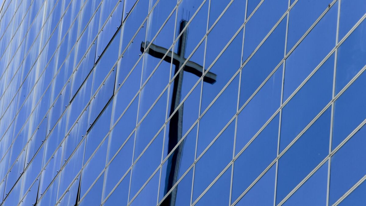 The cross atop the Tower of Hope is reflected in the former Crystal Cathedral in Garden Grove.