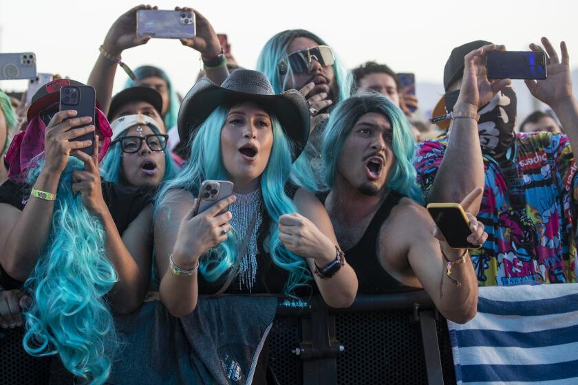 INDIO, CA - APRIL 17, 2022: Wearing the signature blue wigs of Karol G, music fans sing-along as Karol G energizes the crowd on the main Coachella stage to perform on day three of the Coachella Music Festival on April 17, 2022 in Indio, California.(Gina Ferazzi / Los Angeles Times)