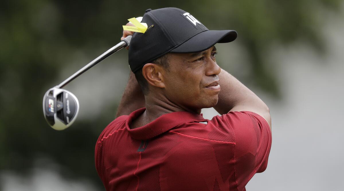 Tiger Woods in a red shirt swinging a golf club