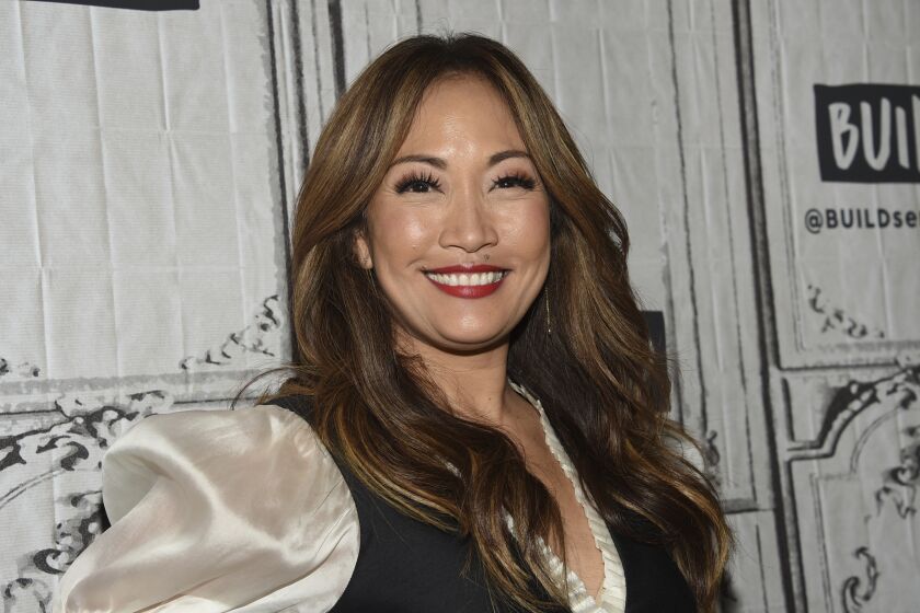 Carrie Ann Inaba smiles in a cream silk blouse and black vest