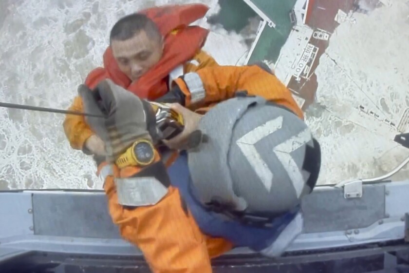 In this image released by Hong Kong Government Flying Service, helicopter crew members winch up a man from a sinking ship in the South China Sea, 300 kilometers (186 miles) south of Hong Kong, Saturday, July 2, 2022, as Typhoon Chaba was moving in the area. The industrial support ship operating in the South China Sea has sunk with the possible loss of more than two dozen crew members, rescue services in Hong Kong said Saturday. (Hong Kong Government Flying Service via AP)