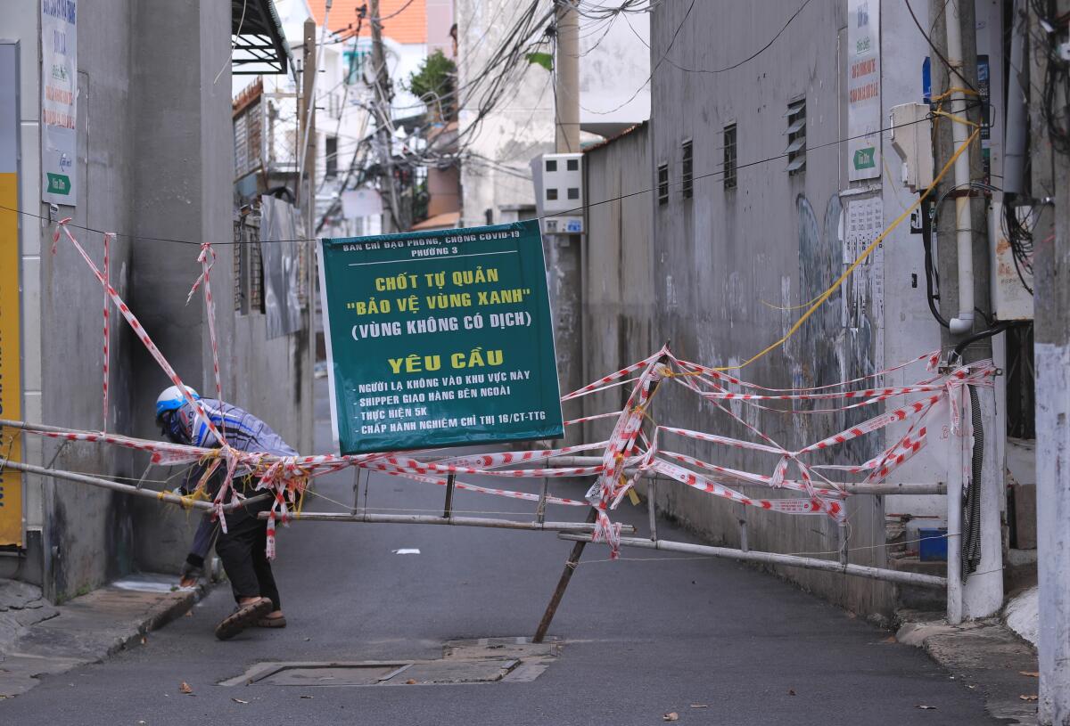 A man slips through a barricade to enter an alley in Vung Tau, Vietnam.