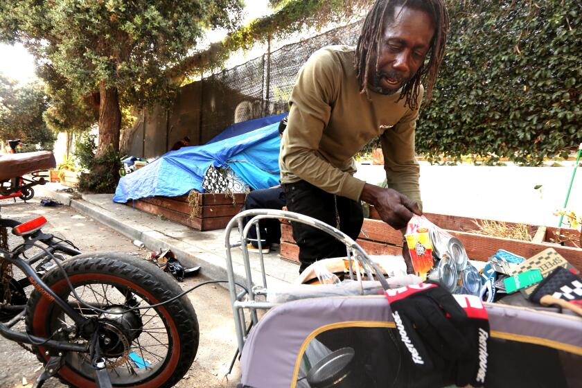 VENICE, CA - JULY 10, 2024 - Patrick Baxter, 60, who has been homeless for 34 years, looks through his only belongings near a homeless encampment along 200 Grand Canal Street a block from where the Venice Dell Project is to be built as housing for the homeless in Venice on July 10, 2024. Baxter says he keeps everything with him because past city clean ups of homeless encampments in the area have taken all that he had, including his dog. He said he's frustrated with the lack of housing for the homeless. He was living homeless on Hampton Ave. in Venice last year when many homeless were given housing as part of the Inside Safe program. He said he was not offered housing. Advocates for low-income housing are suing the city of Los Angeles this week accusing City Council member Traci Park, City Atty. Hydee Feldstein Soto and other officials of violating fair housing laws by allegedly blocking a planned affordable housing development in Venice. The Venice Dell project is to include 140 units of housing for low-income and formerly homeless residents on what's now a city-owned parking lot along the neighborhood's famed canals. (Genaro Molina/Los Angeles Times)