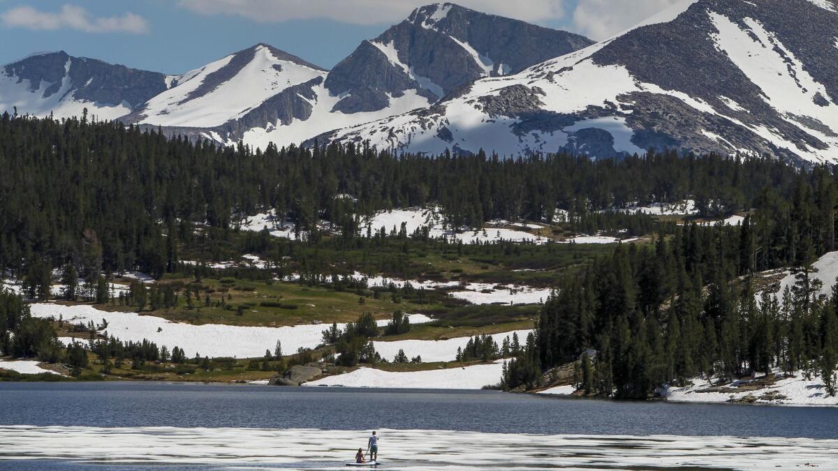 Stand-up paddle boarders at Tioga Lake west of Lee Vining in July 2017. Warmer temperatures from climate change mean California's mountains will get less snow, more rain and snowpack will melt earlier, making it tougher to capture the water.