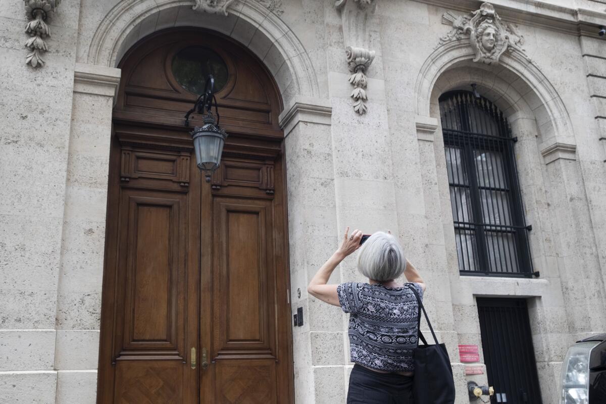 A woman photographs a stone facade with a door