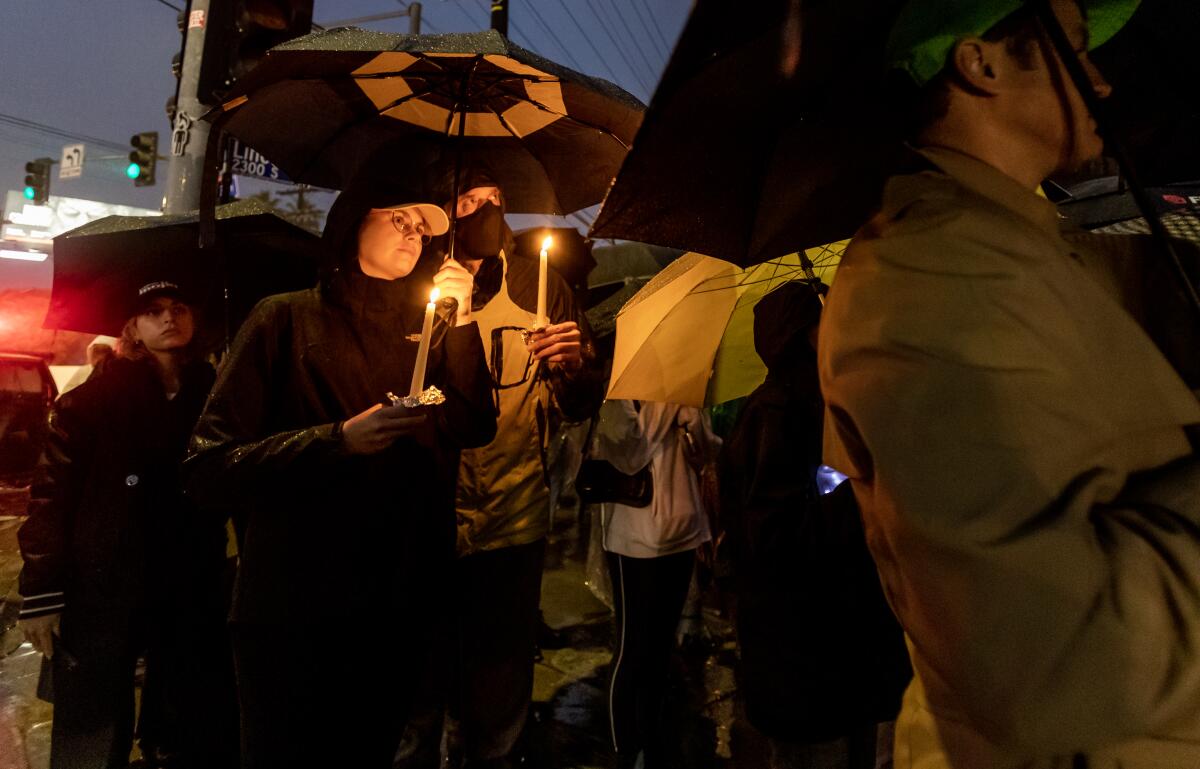 People with umbrellas hold lit candles