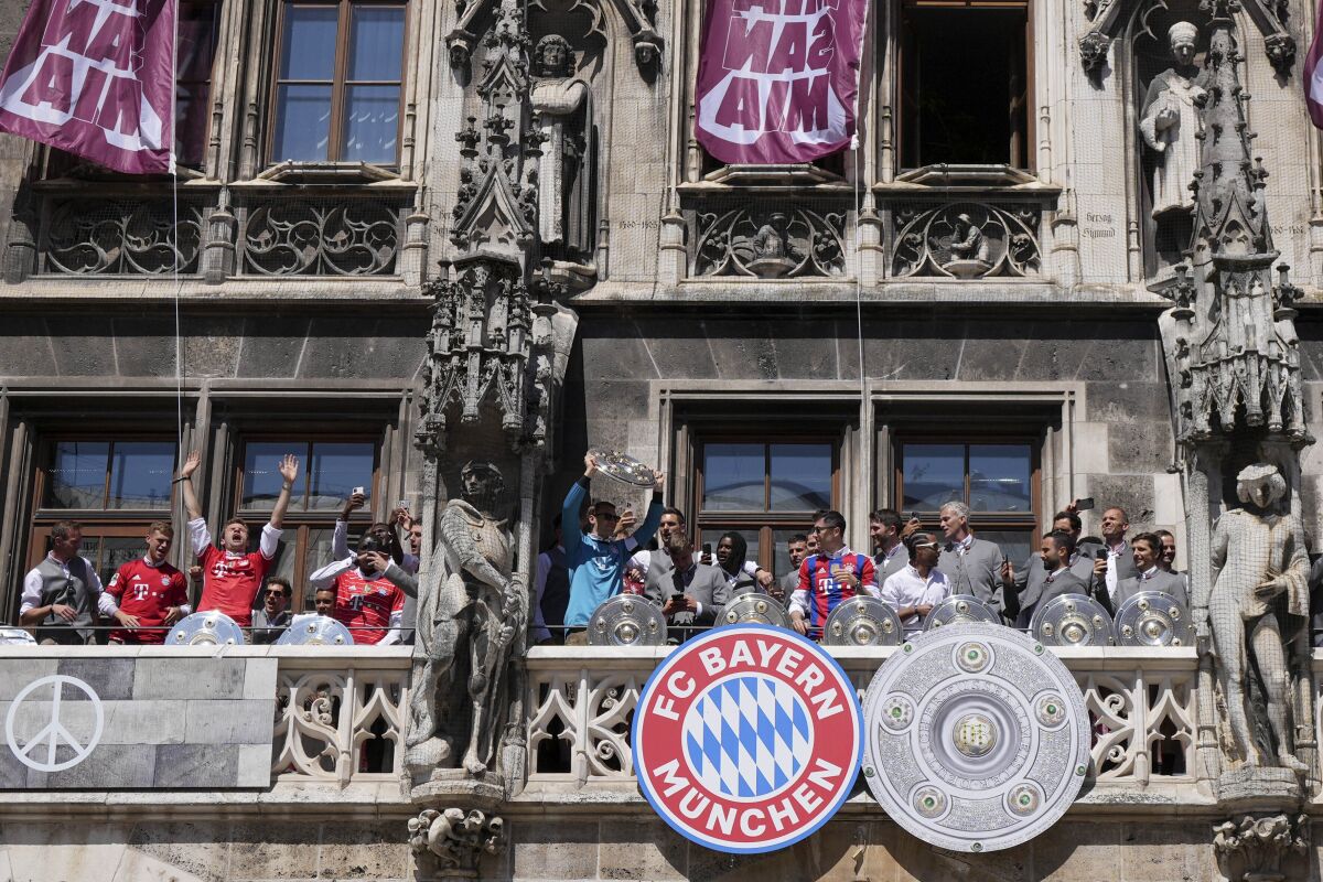 Bayern goalkeeper Manuel Neuer lifts the trophy besides his teammates on the balcony of the town hall at Marienplatz square celebrating the 31th Bundesliga title at the German Bundesliga in Munich, Germany, Sunday, May 15, 2022. (AP Photo/Matthias Schrader)