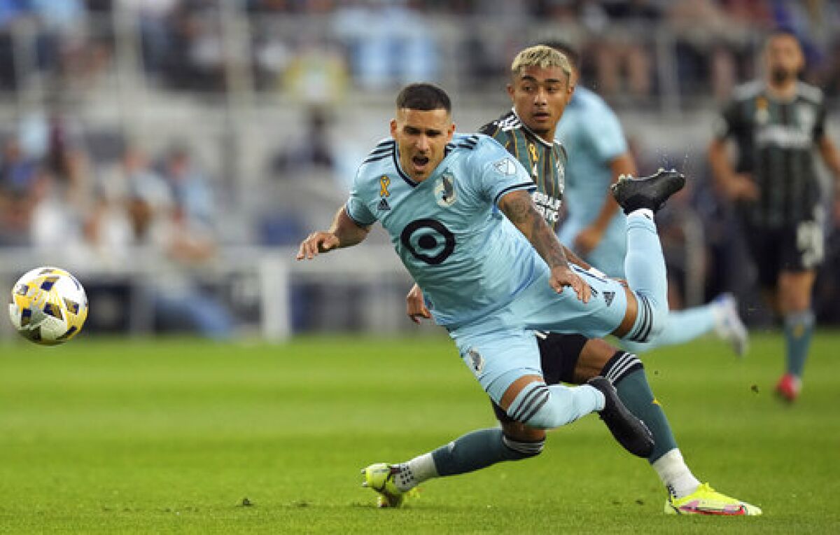 Minnesota United midfielder Franco Fragapane (7) goes flying as LA Galaxy defender Julian Araujo (2) stuck his foot out to defend during the first half of an MLS soccer match Saturday, Sept. 18, 2021, in St. Paul, Minn. (Anthony Souffle/Star Tribune via AP)