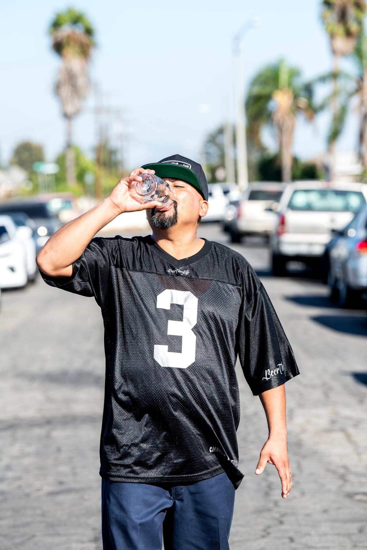 Edgar Preciado, wearing a black football jersey, downs a beer.