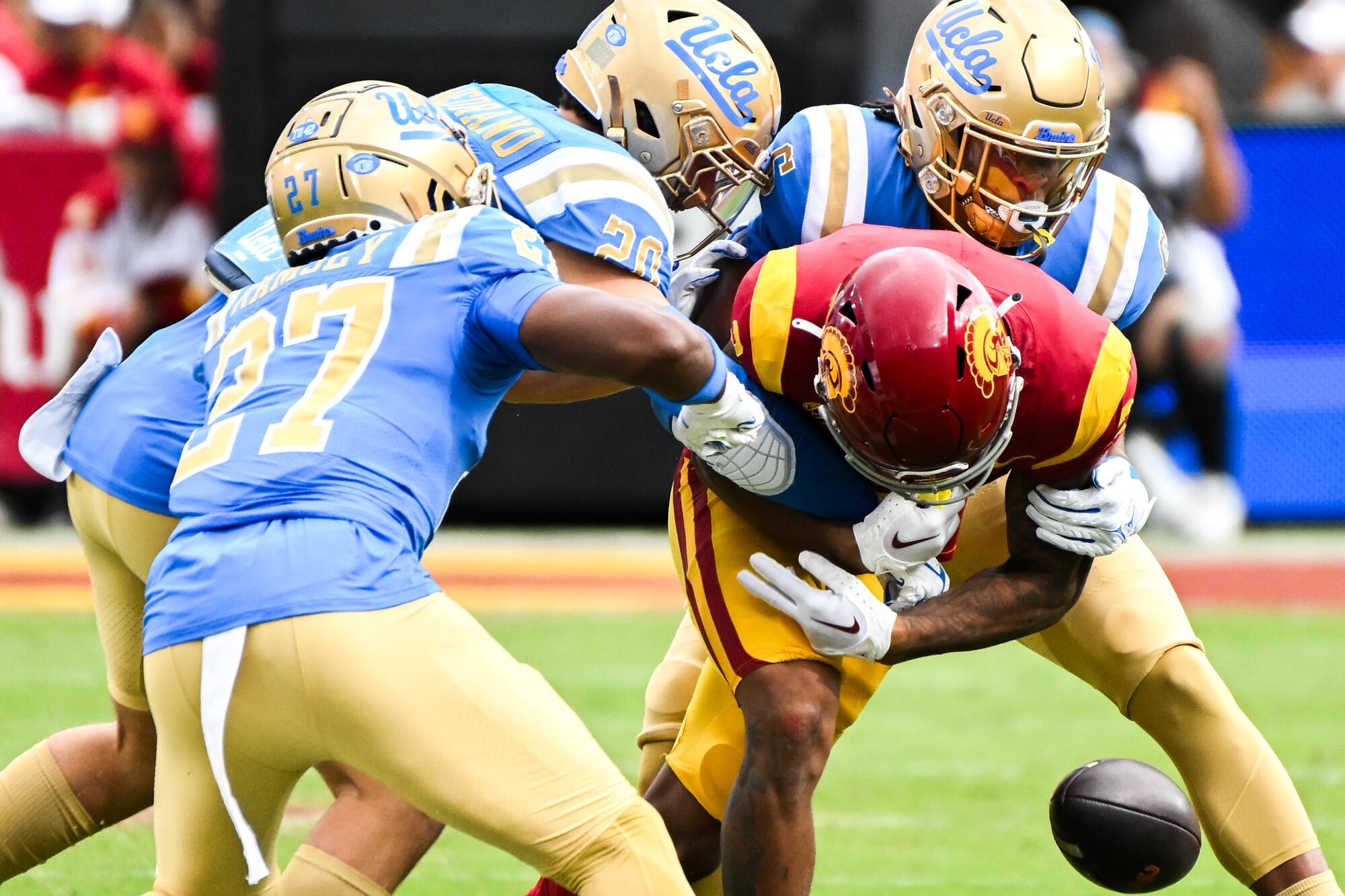 USC's Brenden Rice fumbles the ball while under pressure from UCLA's John Humphrey, Kain Medrano and Kamari Ramsey