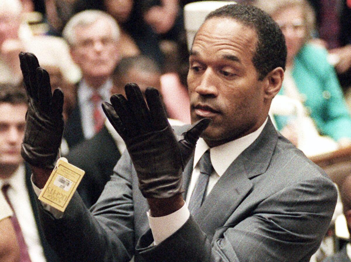 O.J. Simpson, in this infamous 1995 photo, holds up his hands before the jury after struggling to put on a pair of gloves during his double-murder trial in Los Angeles.