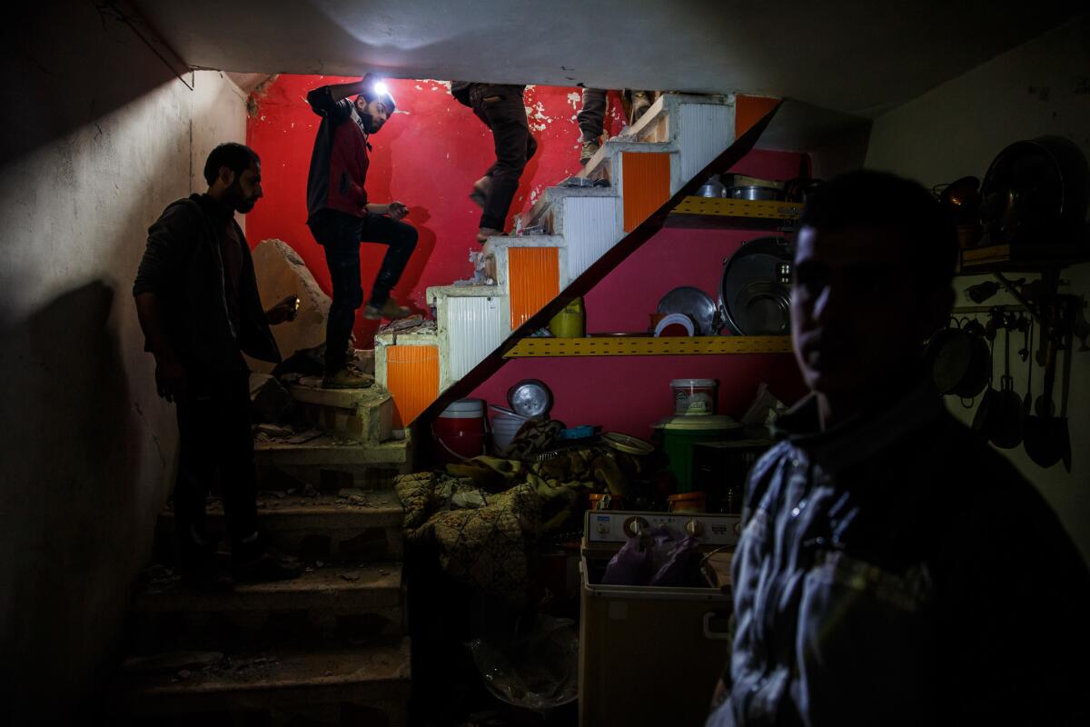 Residents climb out of a basement after showing where family members survived an airstrike by being underground in Mosul, Iraq.