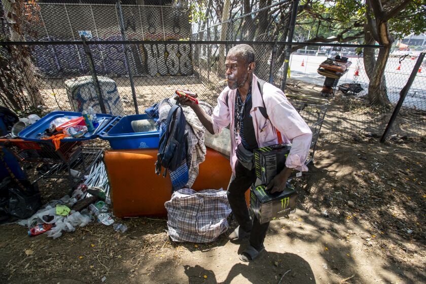 Los Angeles, CA - June 10: After his homeless encampment under the 110 Freeway was removed by the city of Los Angeles for the Summit of the Americas, Calvin Hall, 63, who has been homeless for four years,, returns from grocery shopping through a fenced-off area to a new area near the 110 Freeway and the Los Angeles Convention Center and is hoping the city will put him up in a hotel soon in Los Angeles Friday, June 10, 2022. Los Angeles cleared homeless encampments in and around the Summit of The Americas area. (Allen J. Schaben / Los Angeles Times)