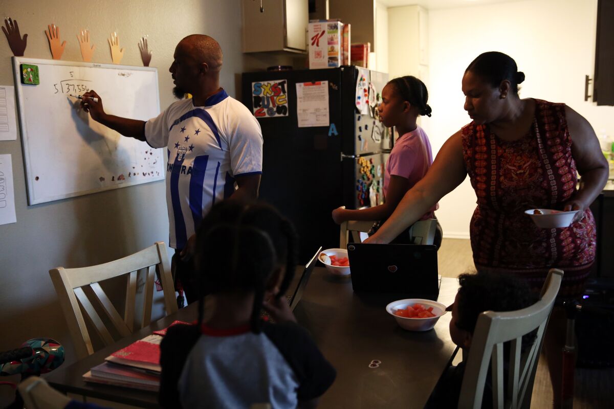 Terrance Stewart helps his daughter, Taylor, with a math problem in their living room in Colton.