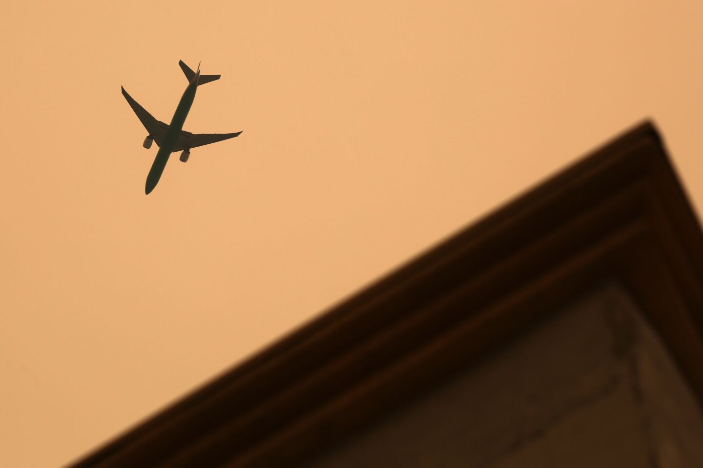 An airplane flies through smoky skies in downtown Los Angeles.